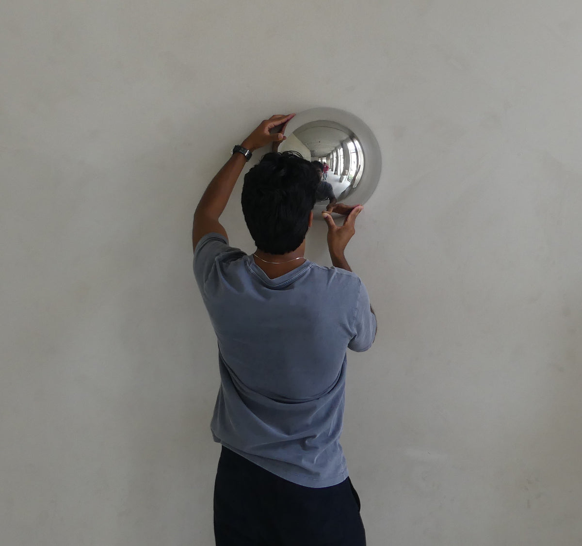 The Lumevre convex mirror being carefully inspected by hand after mounting on a wall